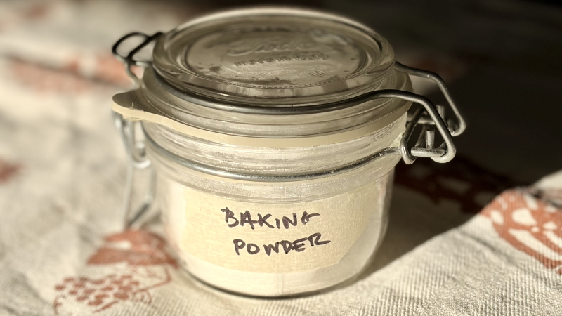 A small airtight jar with a handwritten masking-tape sticker that reads “Baking powder”