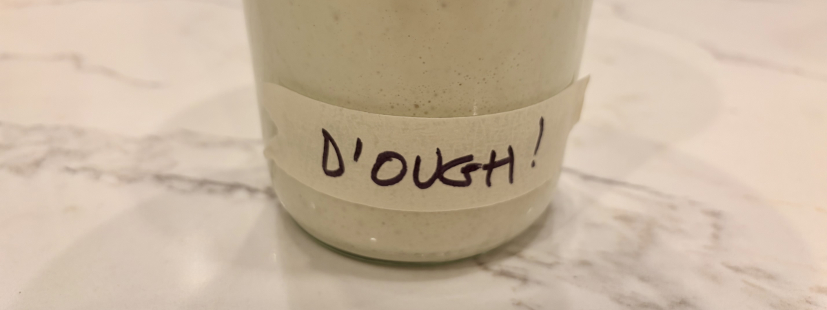 A jar of active sourdough starter, labeled “D’OUGH!”