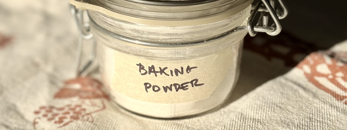 A small airtight jar with a handwritten masking-tape sticker that reads “Baking powder”